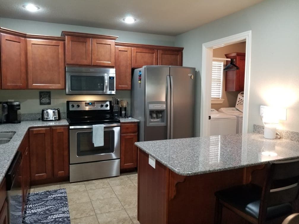 Kitchen with stainless appliances, island seating, and laundry room access