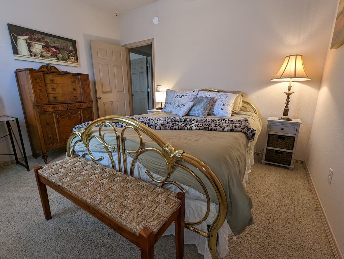 Queen bedroom with brass bed, bench, and dresser